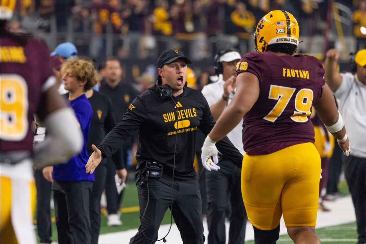 ASU football player and football coach move in for a high-five on the side of the field