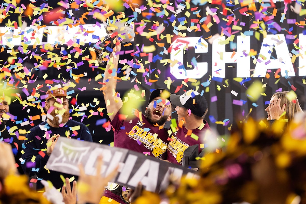 Two football players cheer in celebration as confetti falls.