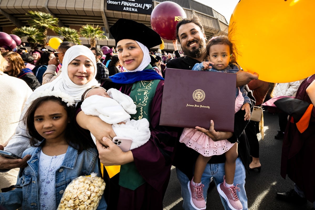 A family including three little girls surround a new ASU graduate