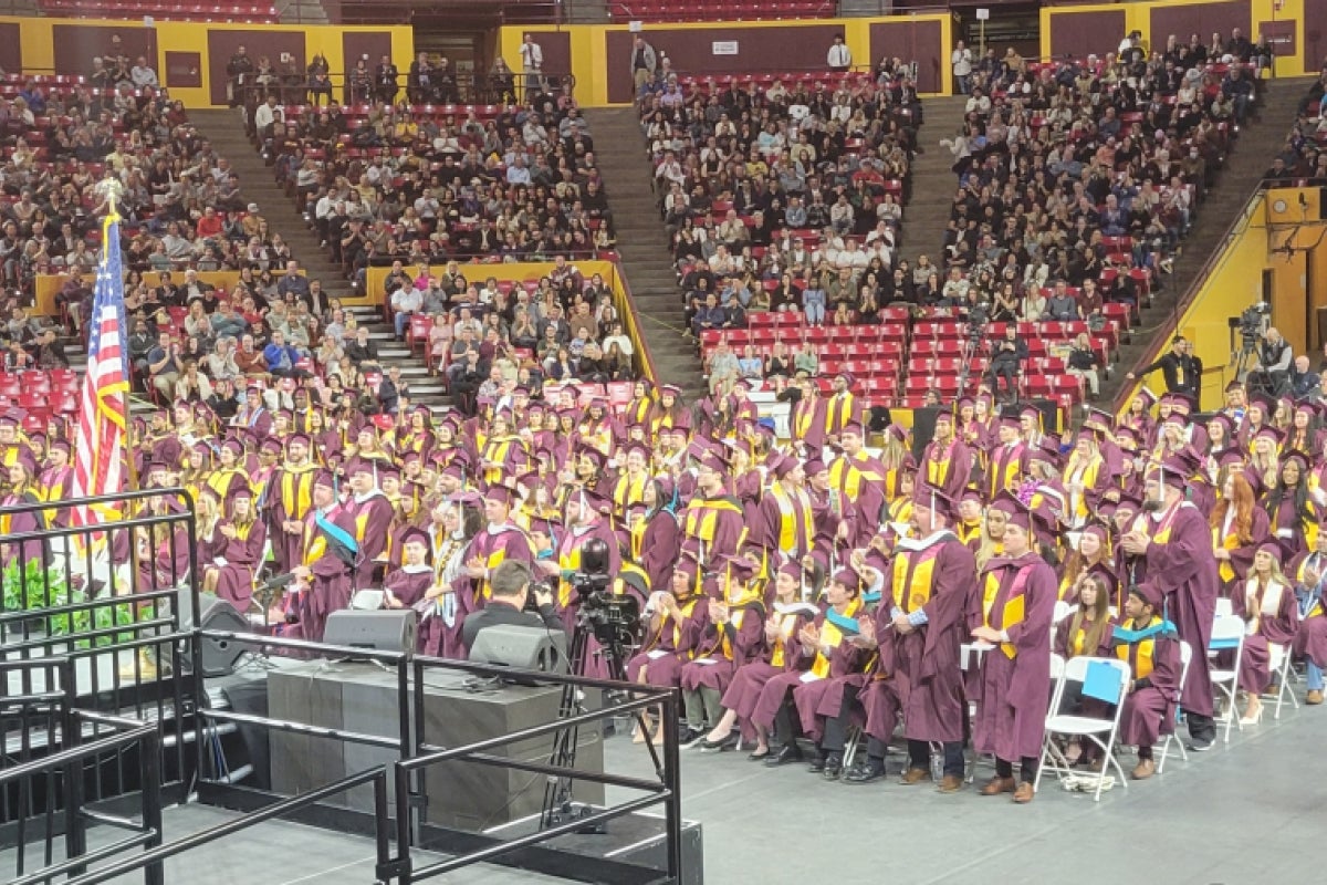 Large arena filled with people in maroon caps and gowns.