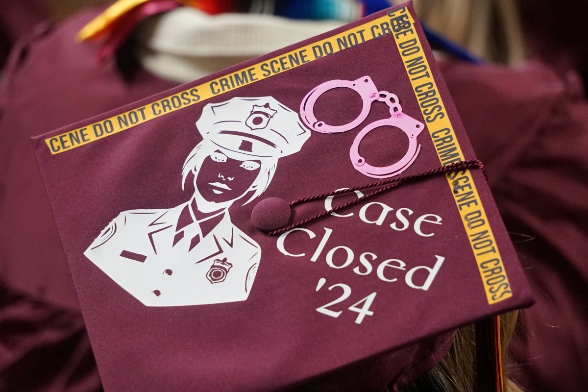 Graduation cap decorated with crime scene tape and an illustration of a police officer.