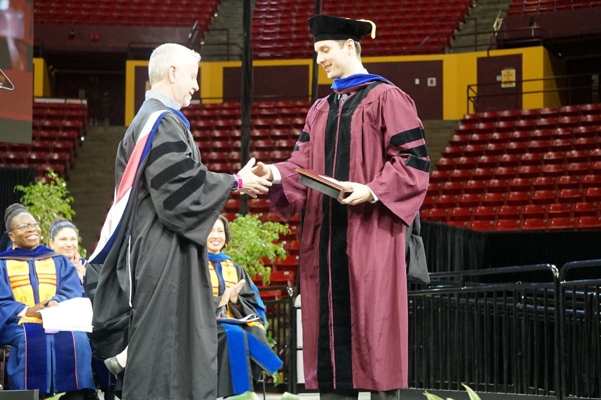 Graduate shakes the hand of a faculty member onstage.