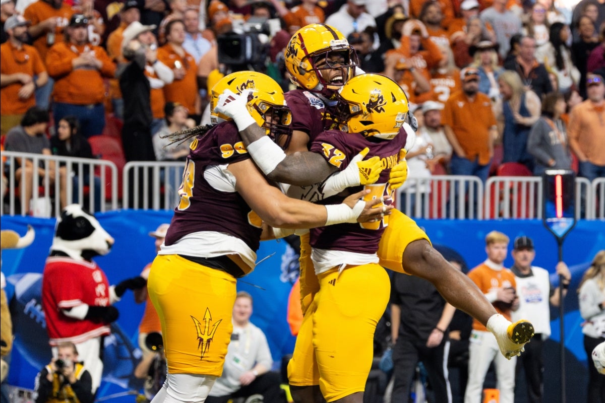 ASU football players jump in the air and embrace in celebration