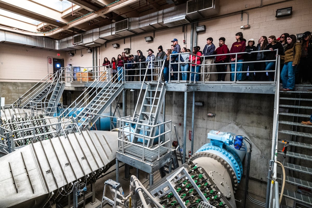 A large group of people gathered looking at water plant equipment