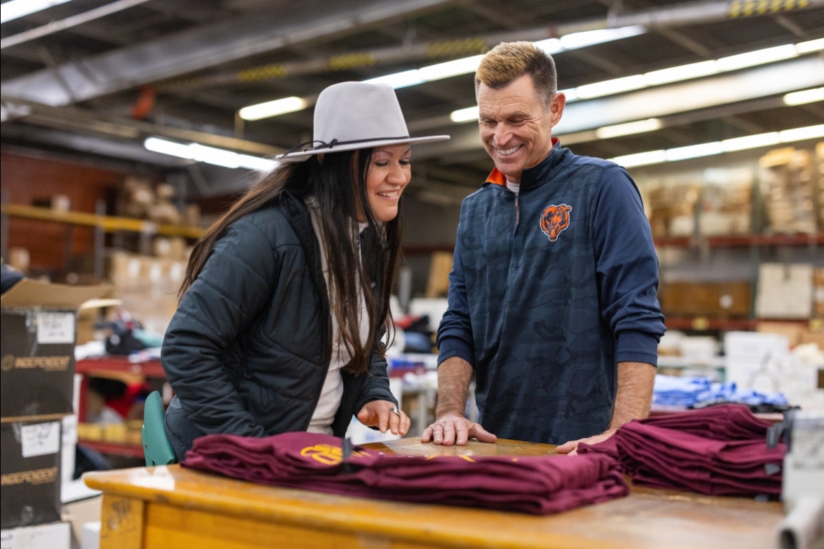 Man and woman looking at a T-shirt on a table and smiling.