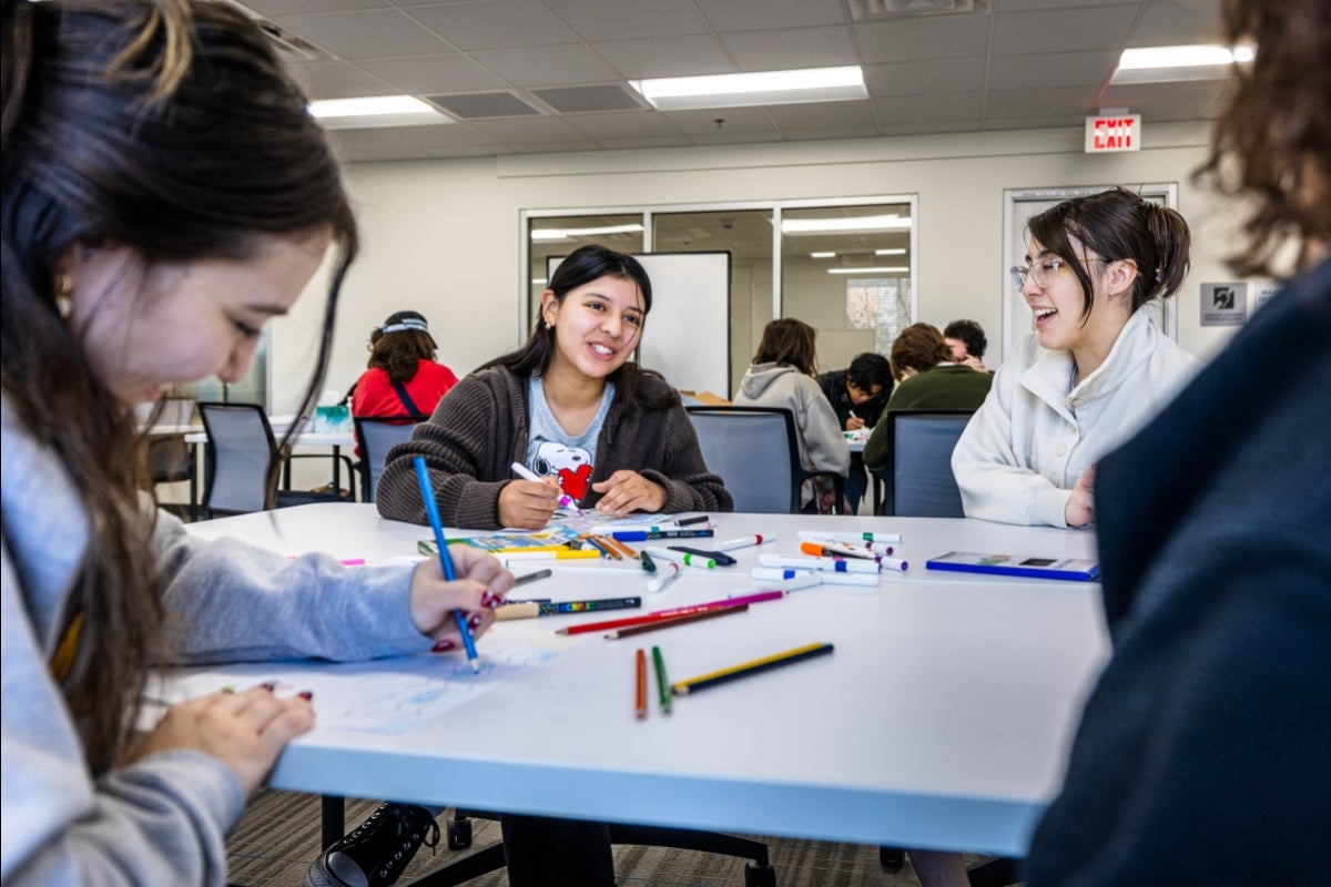 Several young women sit at a table drawing