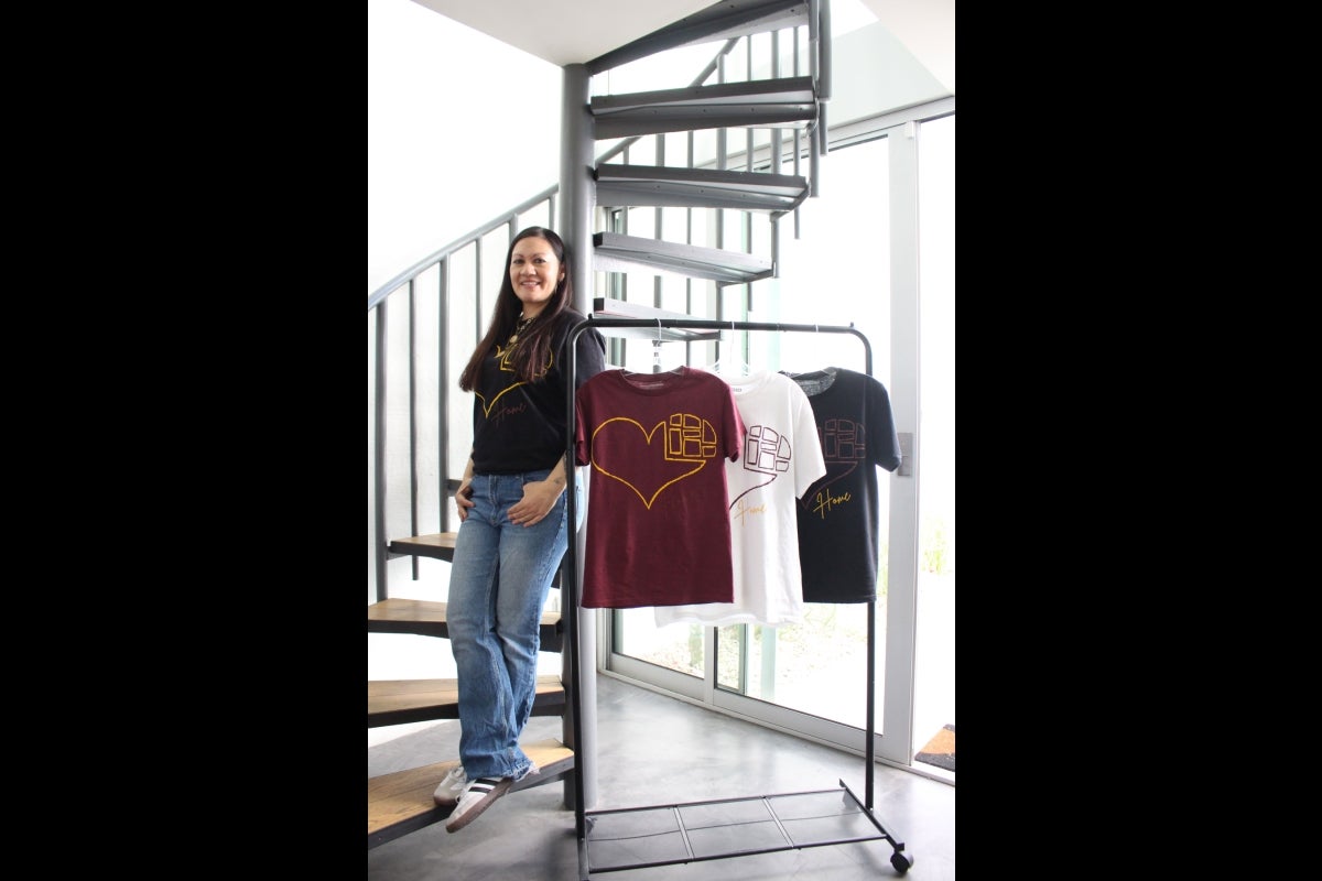 Woman standing on a spiral staircase wearing a T-shirt with a heart graphic on it.