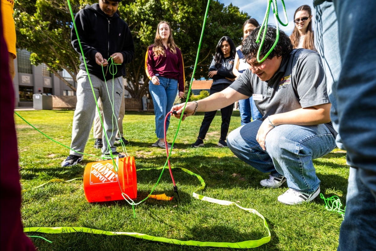 A young man reaches for a bucket while kneeling in a group of people