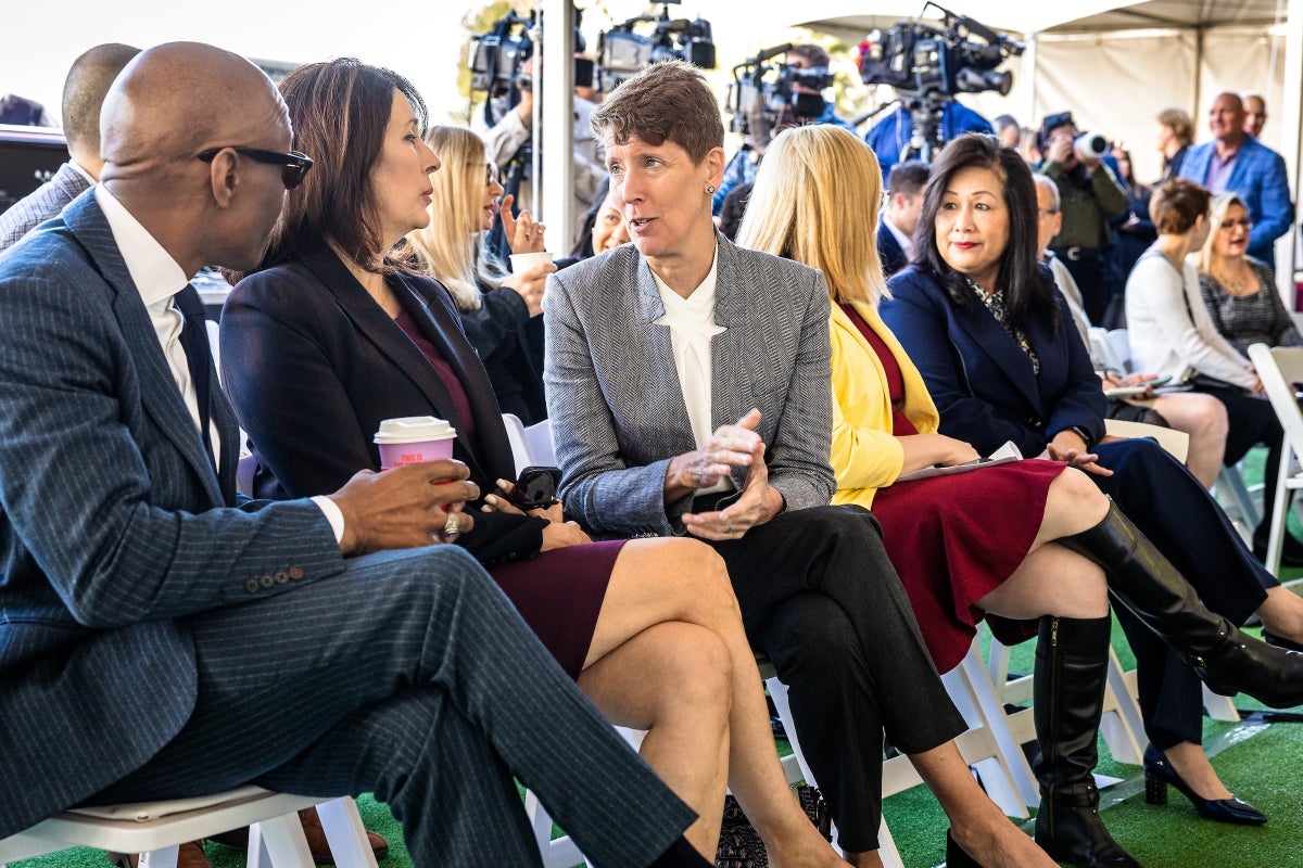 Row of people sitting on chairs at event talking