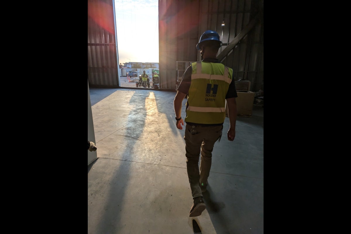 Sun is rising as construction worker walks to construction site.