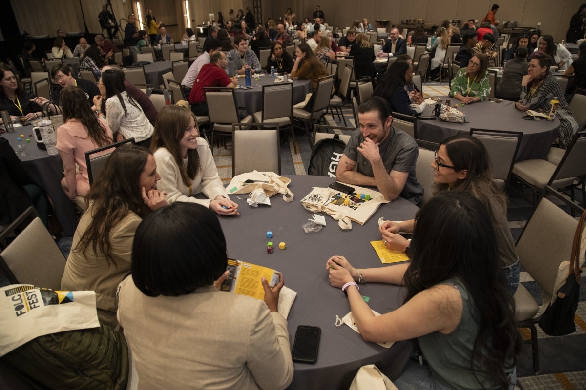 People seated at tables playing a game with dice.