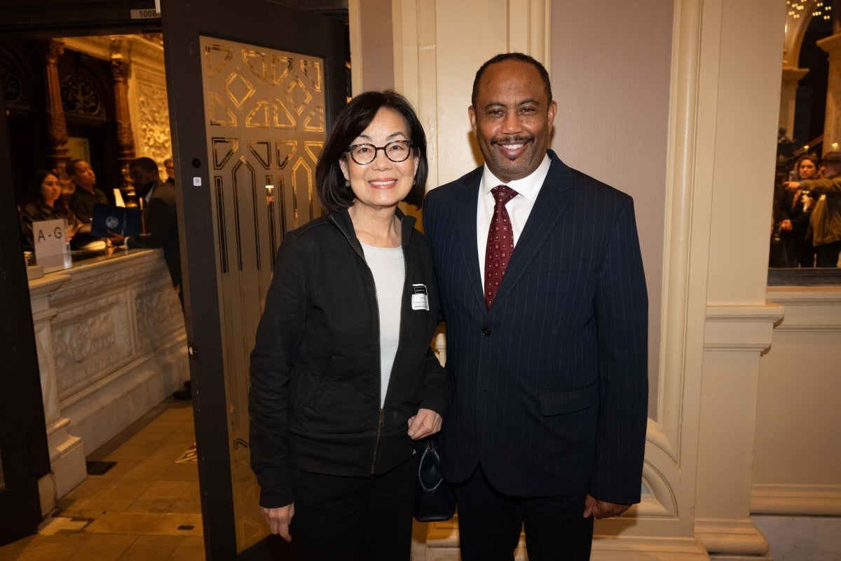 A man and a woman in business attire pose for a photo