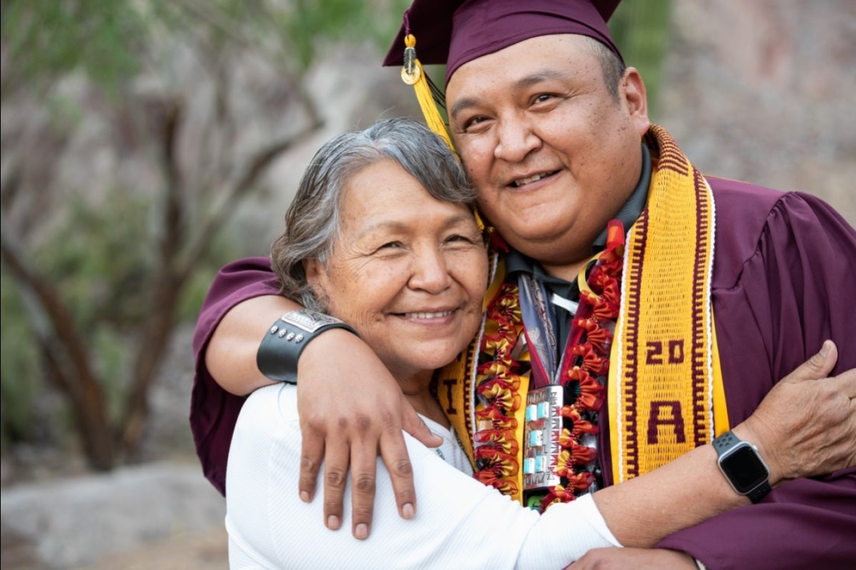 A graduate in cap and gown hugs his sister