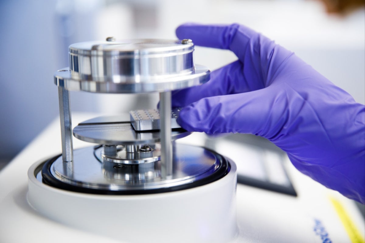 Close-up of a hand putting a cryo-EM grid into a glow discharger, used to clean the grid prior to performing cryo-EM.