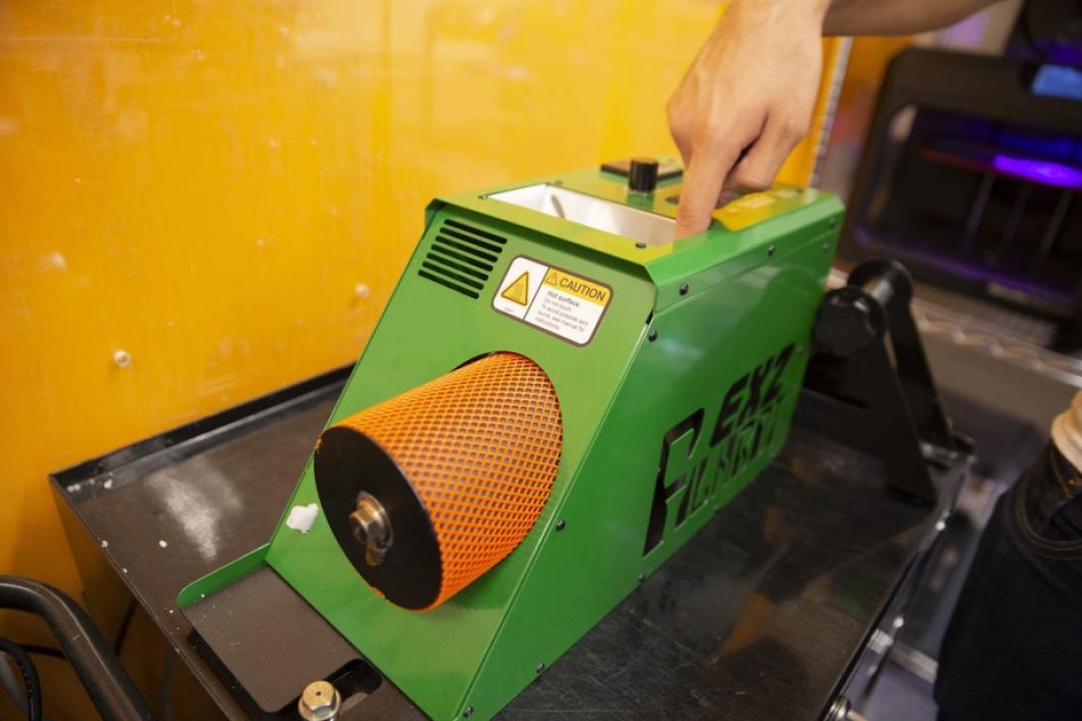 A student demonstrates where the plastic pellets go into the extruder.