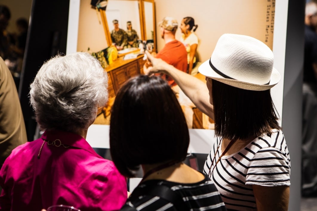 Guests look at a photo display of the Veteran Vision Project, a body of work created by ASU alumnus Devin Mitchell exploring the lives of veterans and their families. 