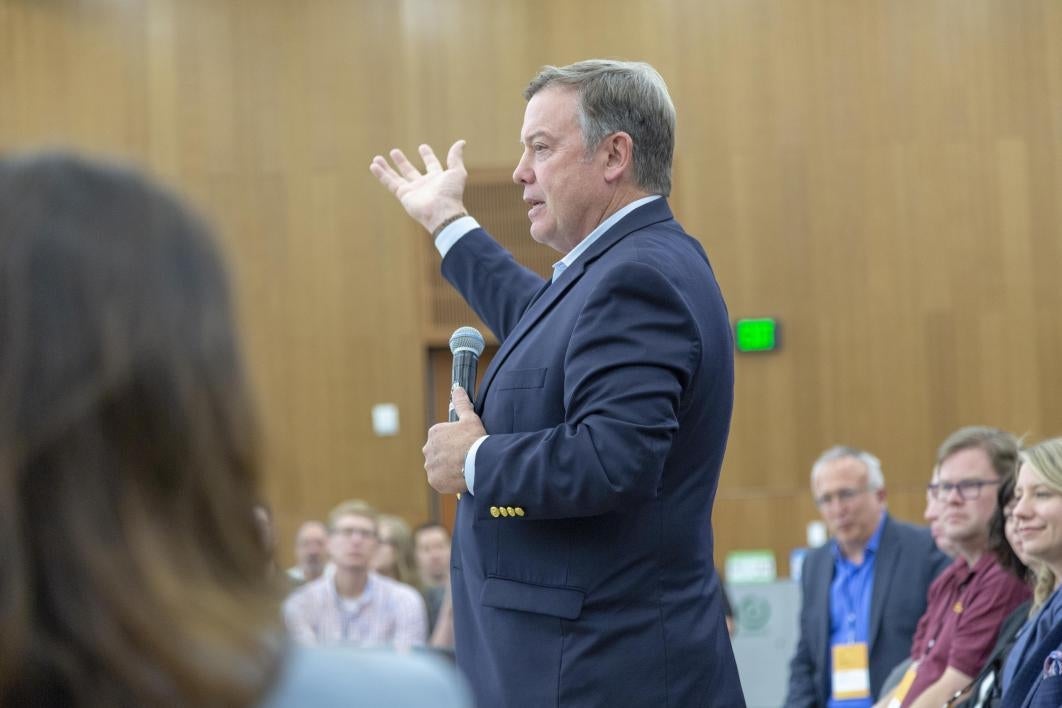 man holding microphone speaking to audience