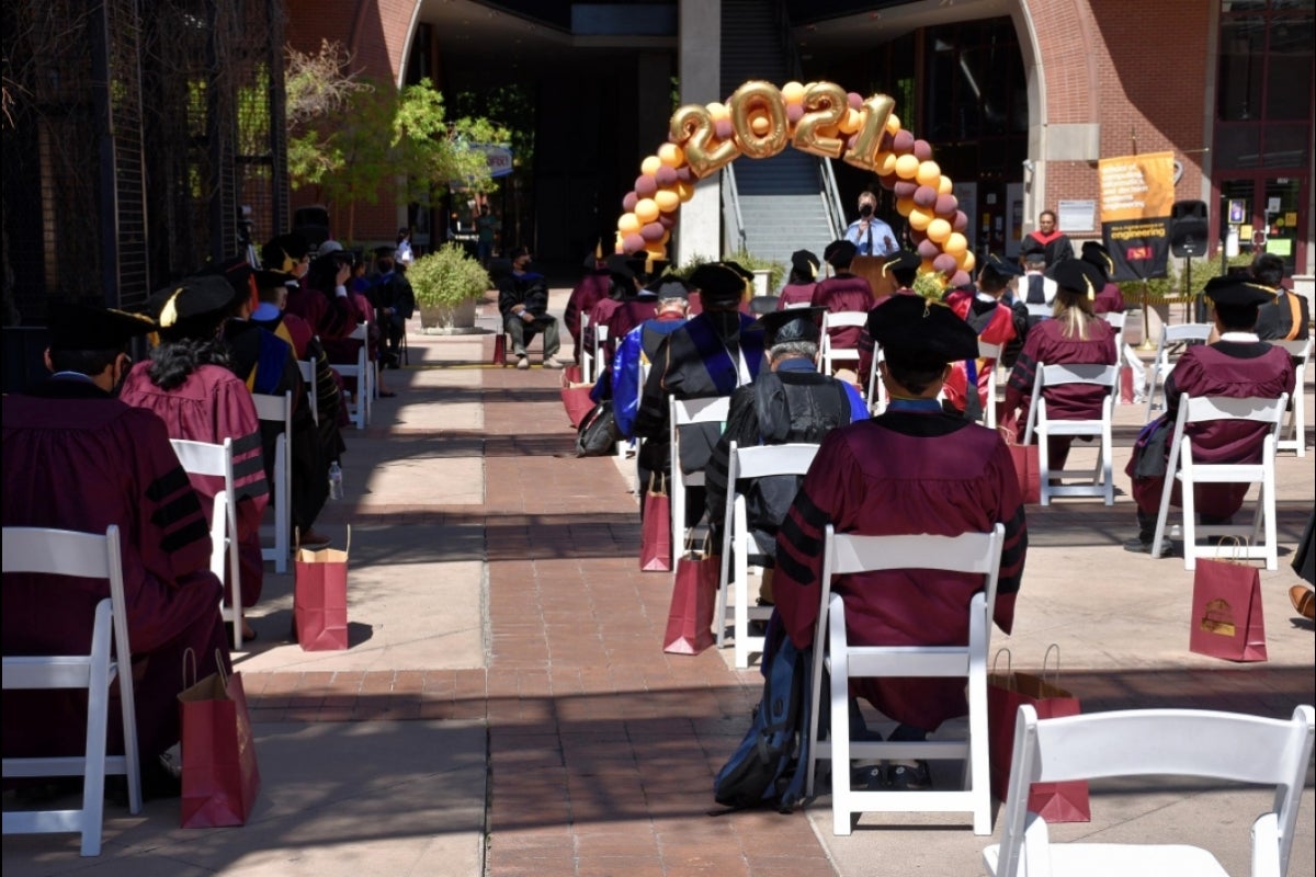 Graduating students sit socially distanced at an outdoor ceremony