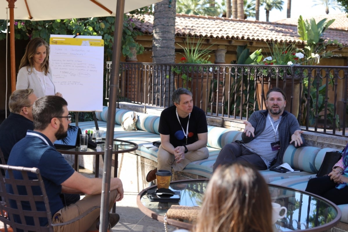 People seated outdoors, having a discussion.