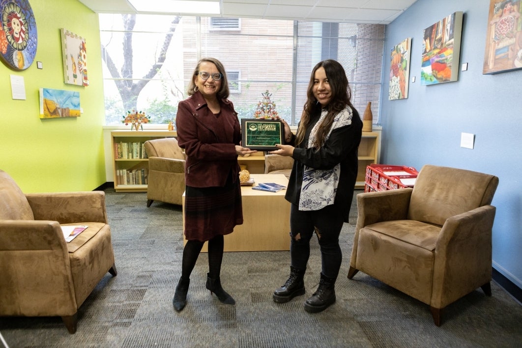 Seline Szkupinski Quiroga and Daniela Fernández Romero hold up the recognition plaque