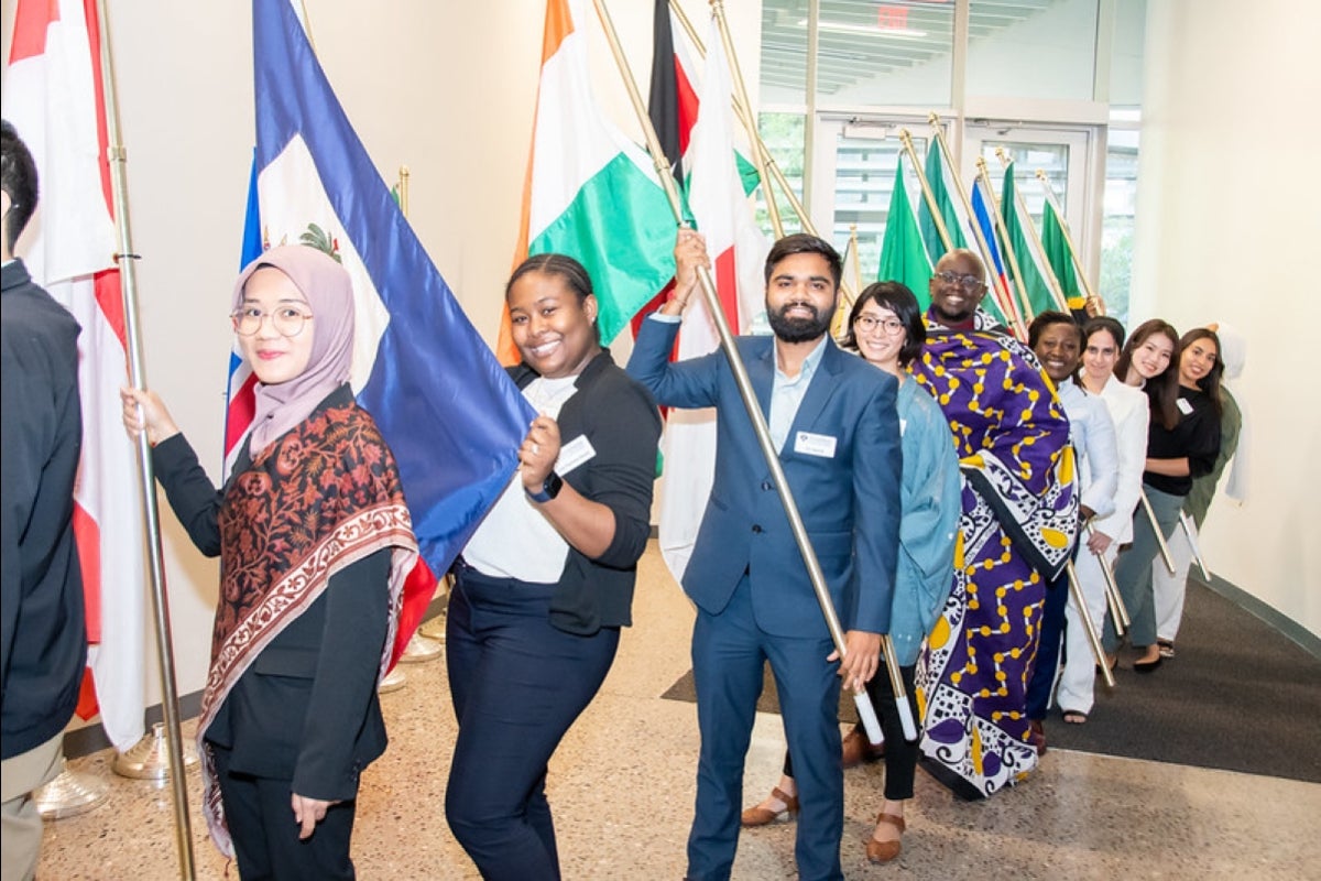 People lined up holding flags and smiling.