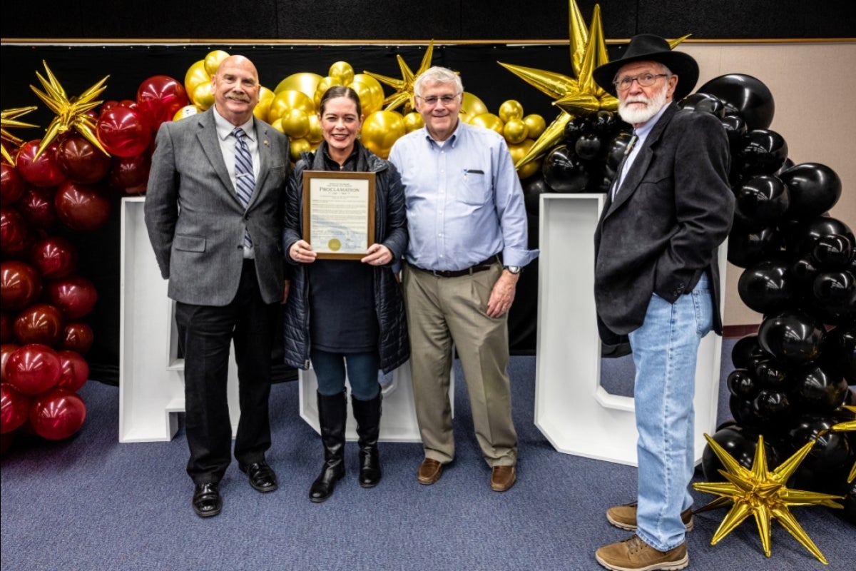 People posing for a group photo holding a plaque with a city proclamation