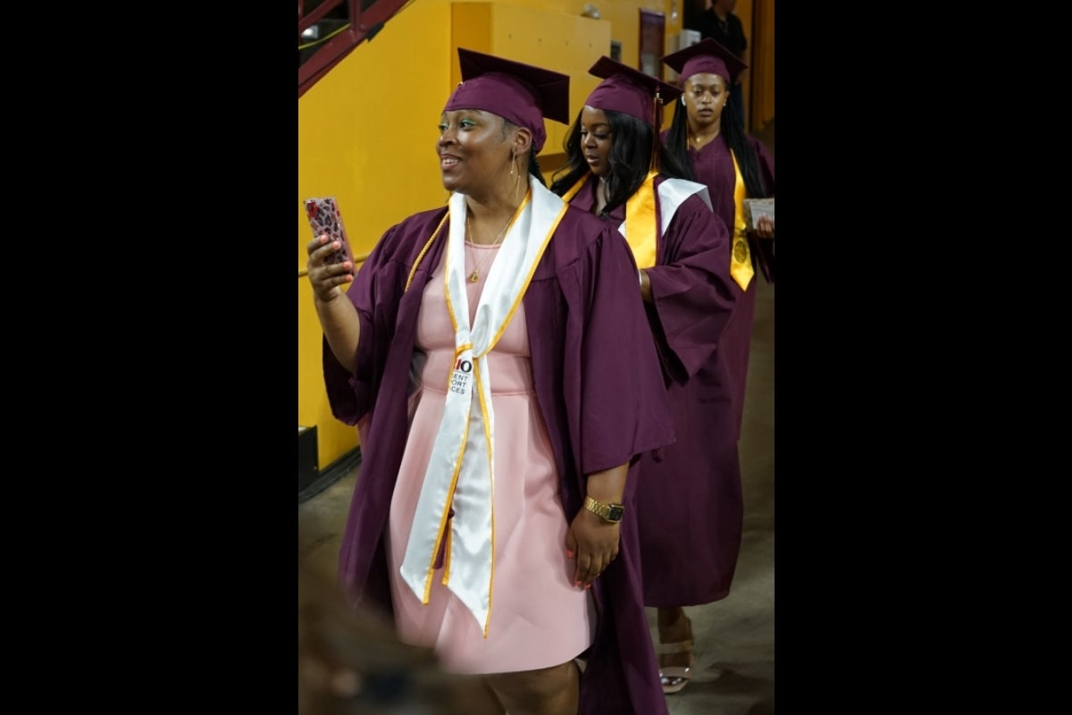 A graduate checks a cellphone while entering convocation.