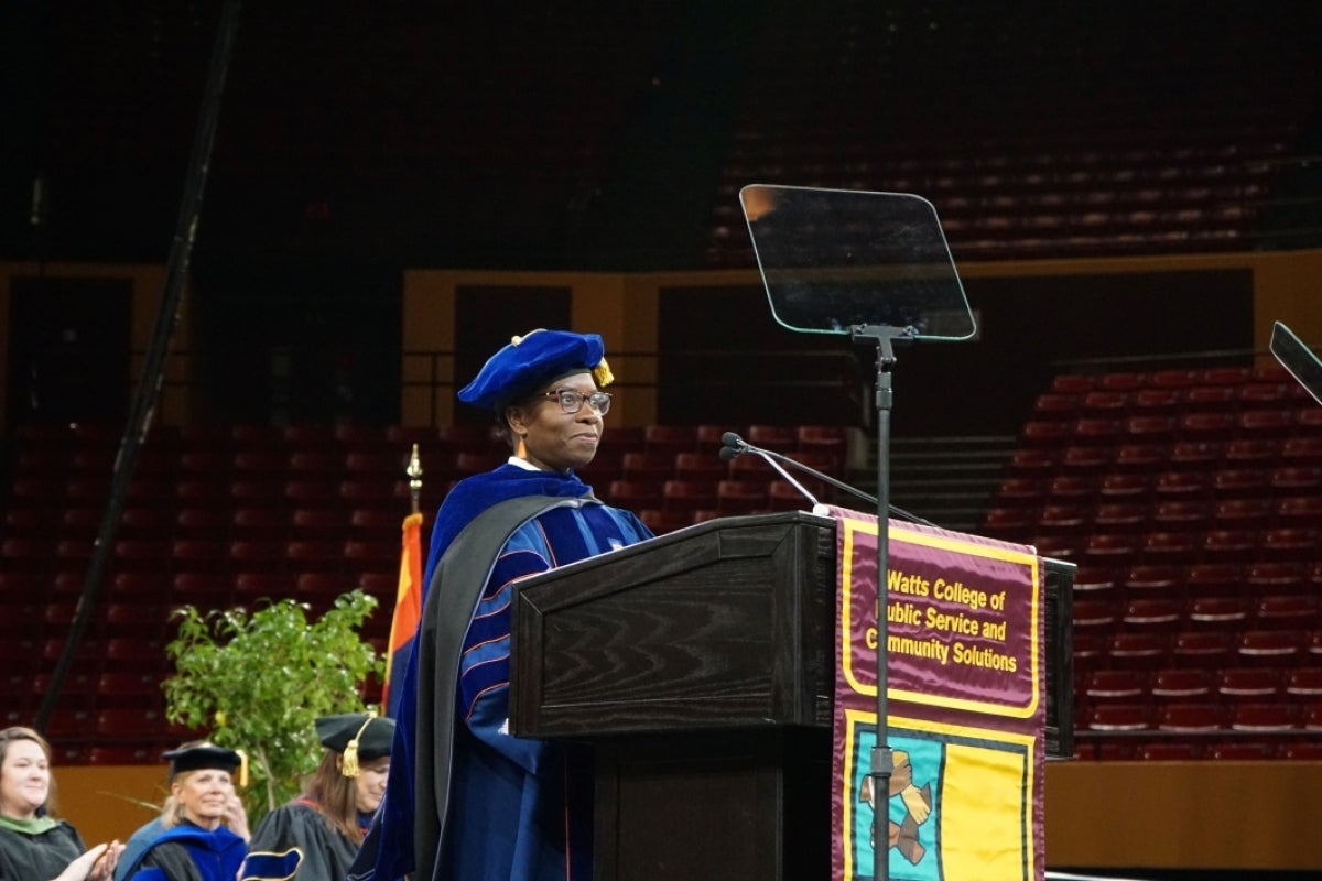 Graduate Christine Buzinde stands at a podium.