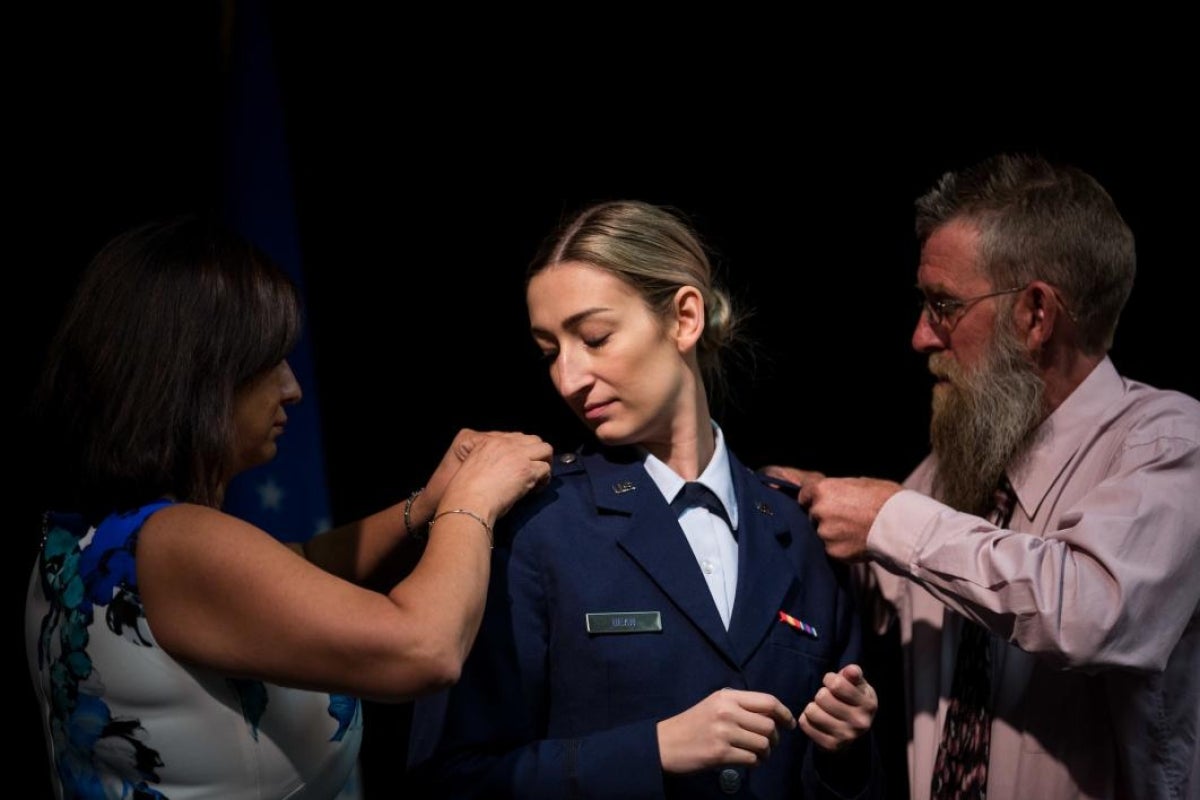 parents pinning bars on daughter's shoulder