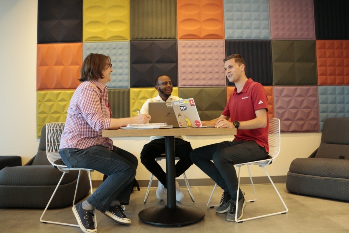 People seated at a workspace talking.