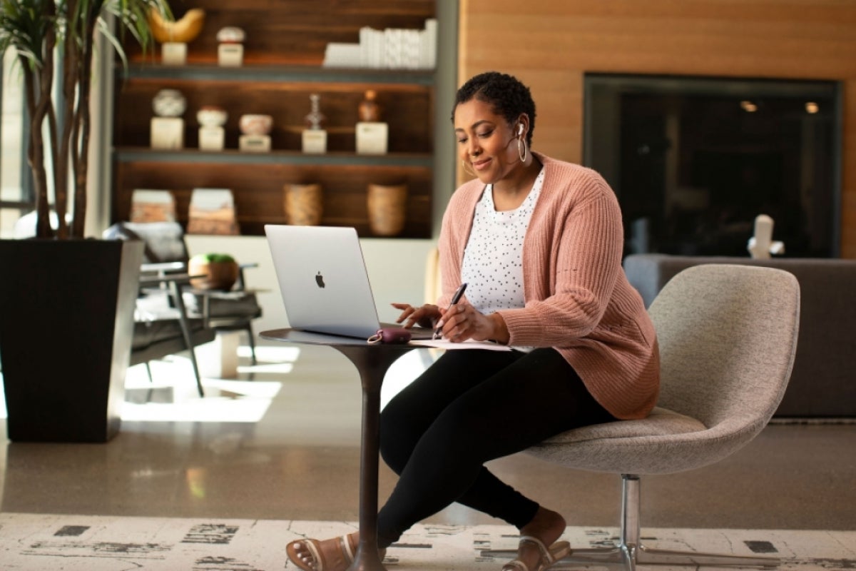 Woman sitting in a lobby using a laptop computer.