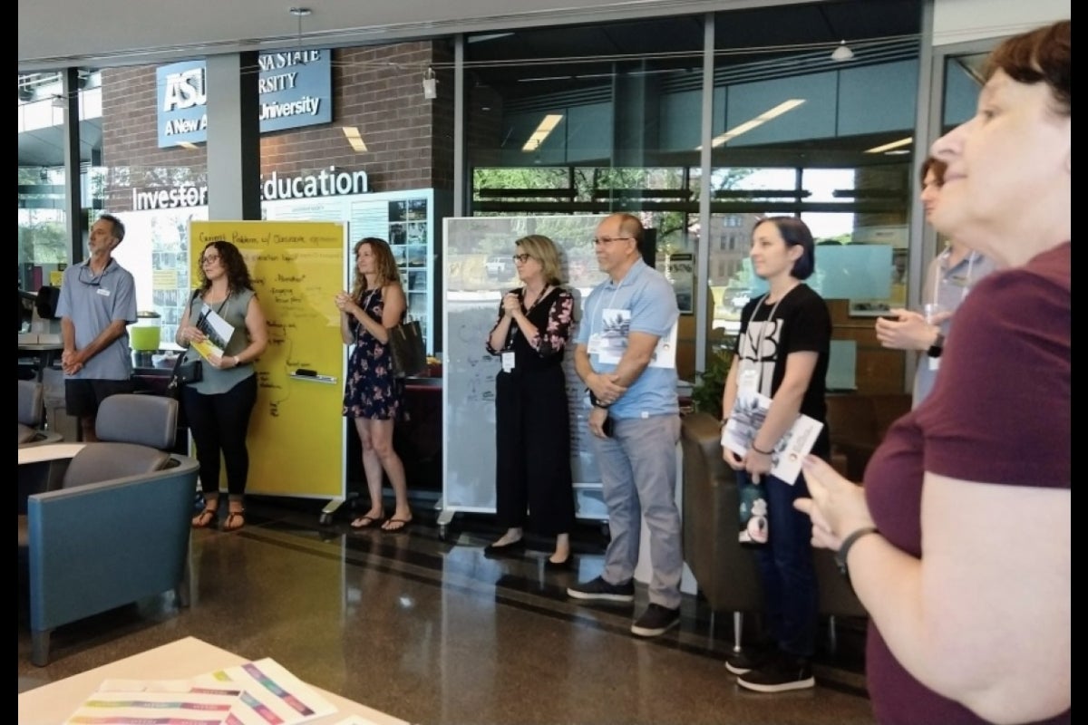 People standing along the perimeter of a room, some clapping.