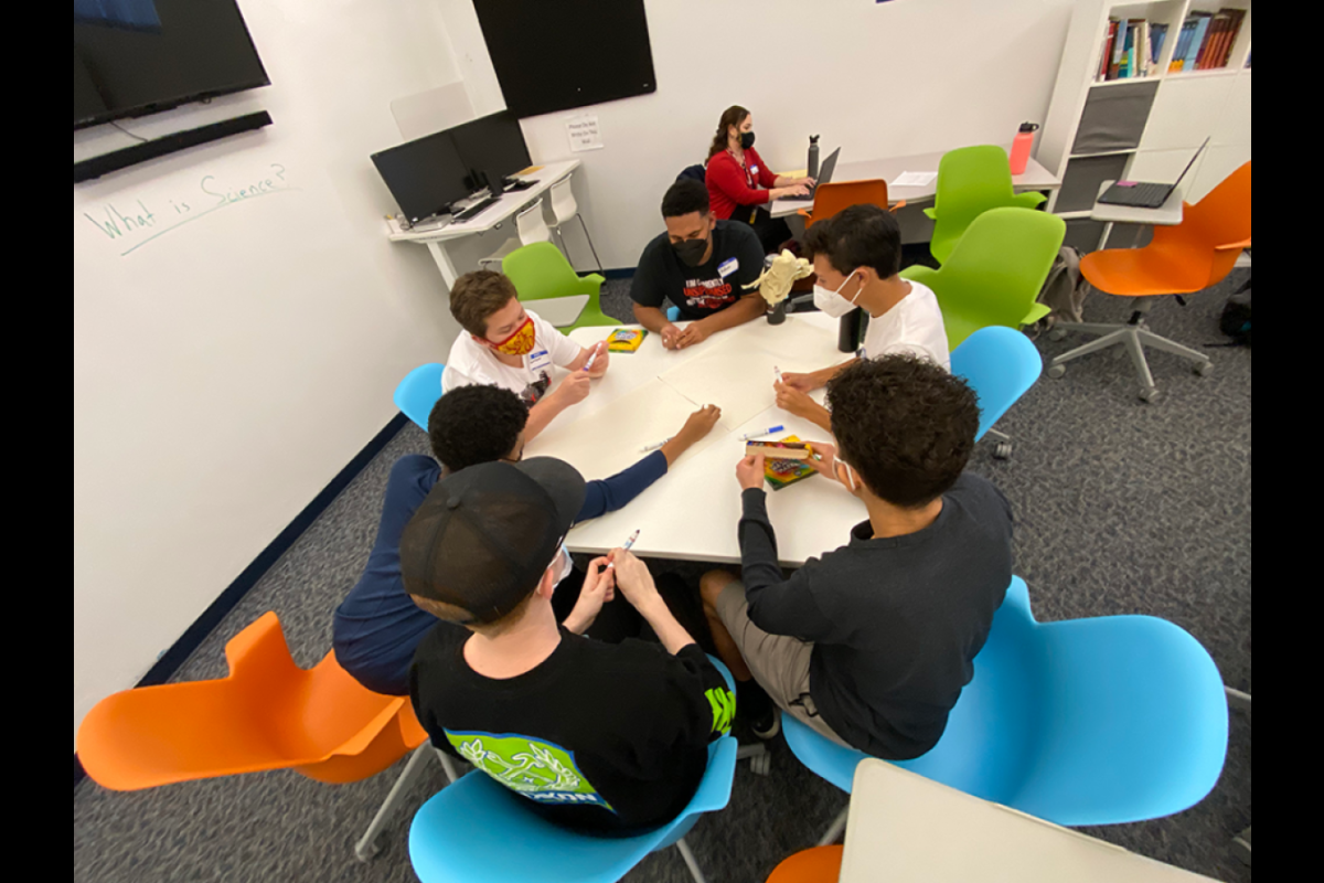 Group of students seated at a table in a classroom.