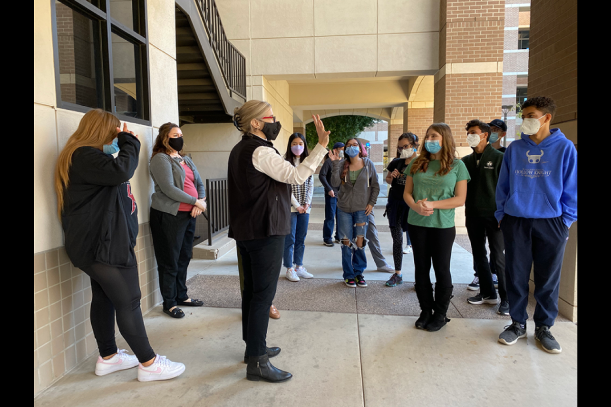 Group of students listening to an instructor in the middle of a hallway.