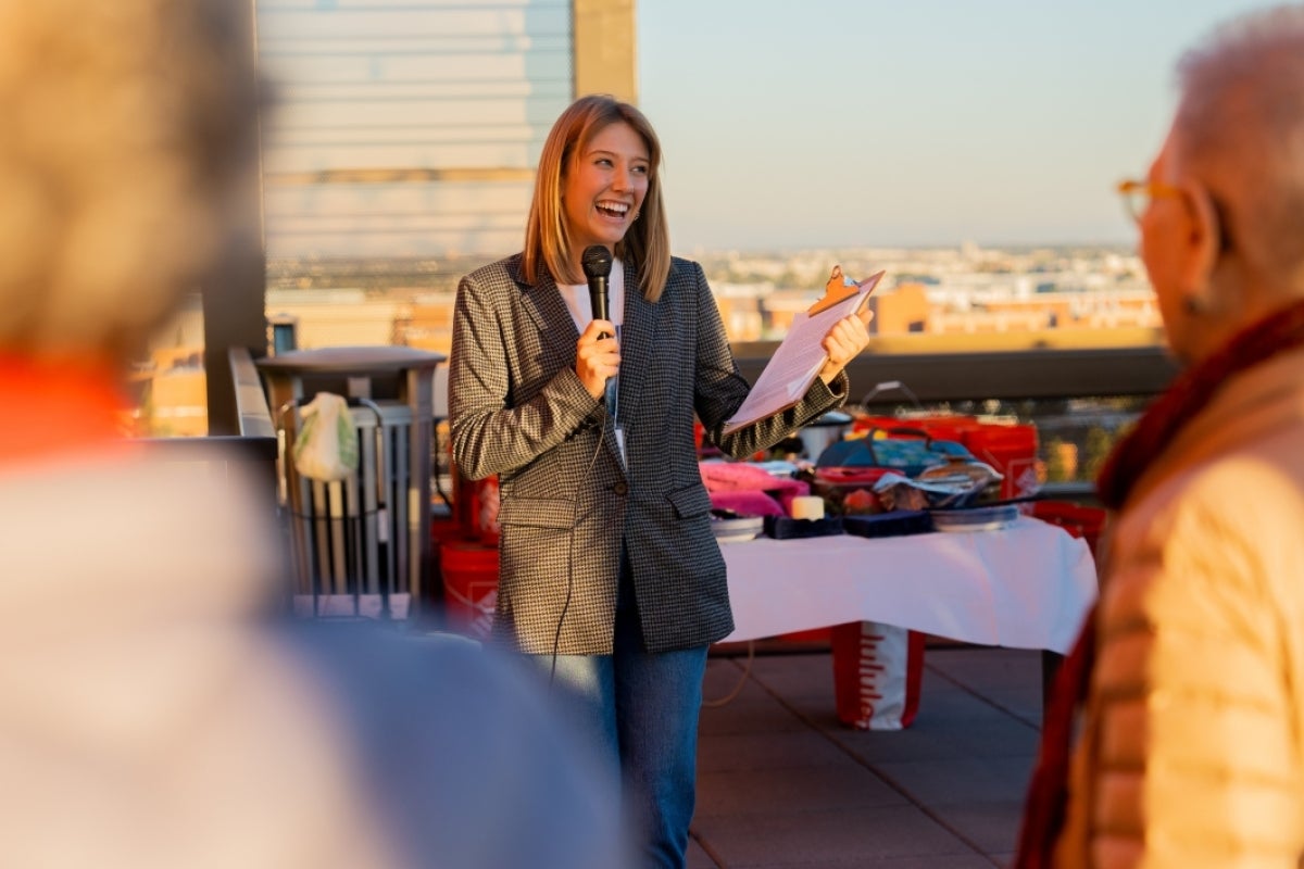 Woman smiling and speaking into a microphone.