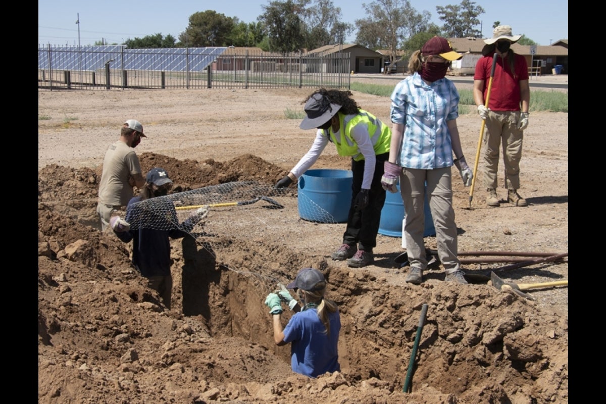 Volunteers standing in and along the trench holding chicken wire