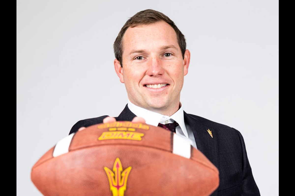 Portrait of coach holding football to camera