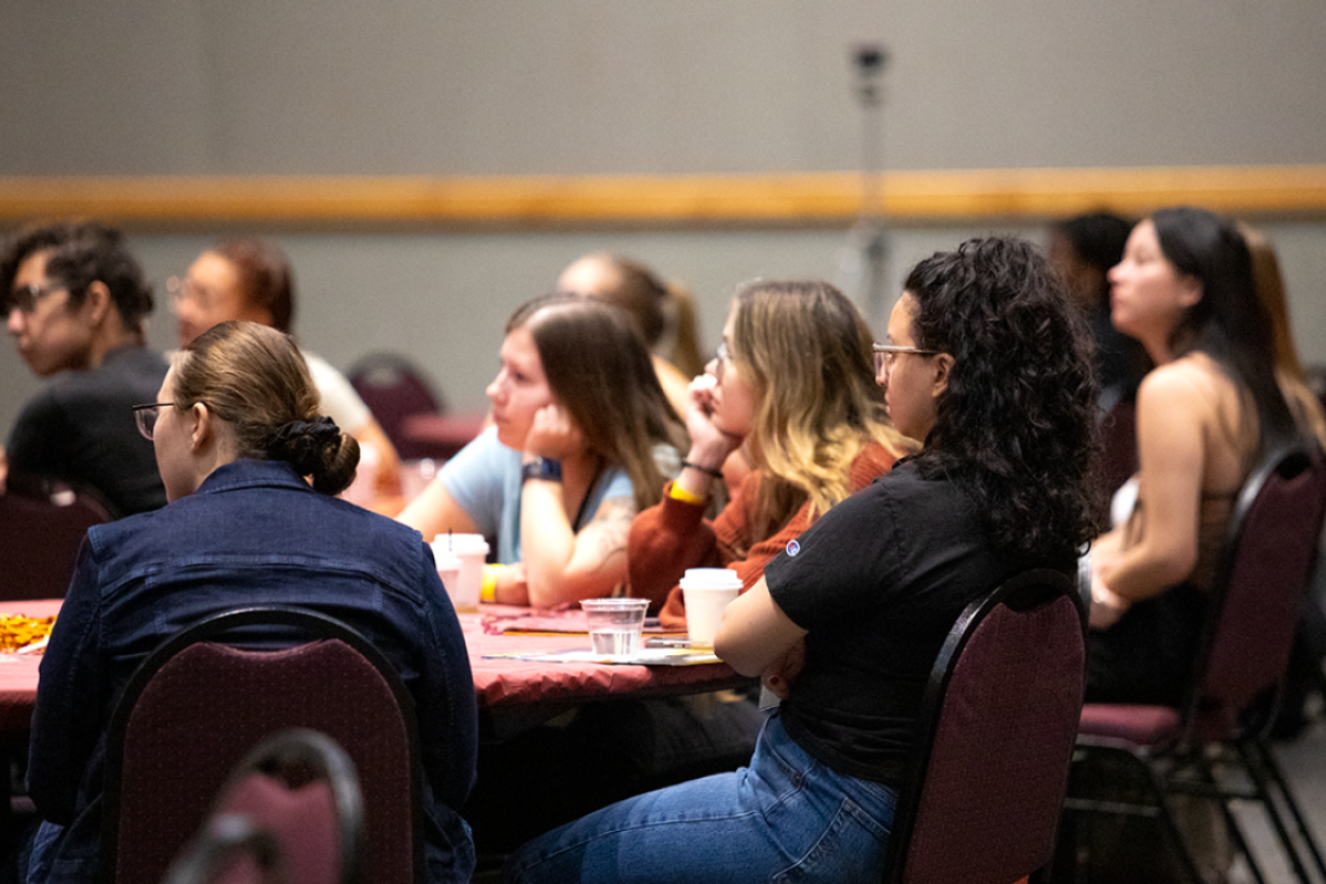 People seated at a table listening to an unseen speaker.