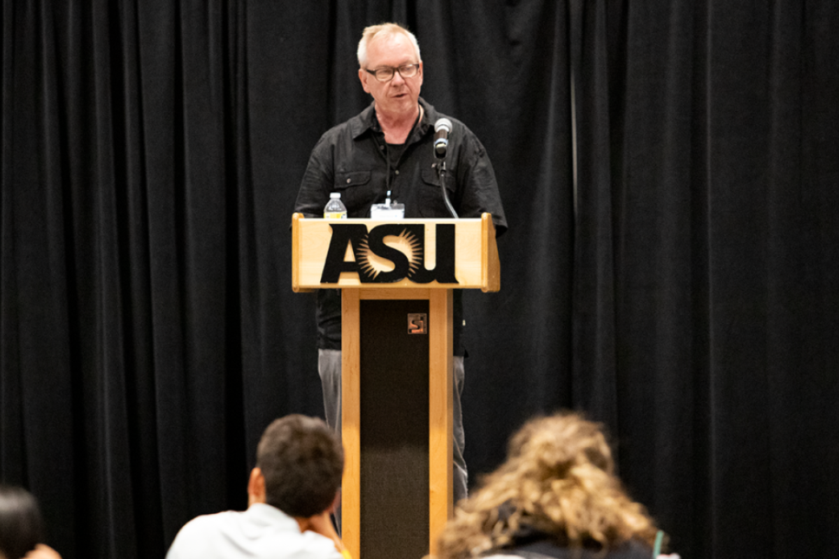 Man standing behind a lectern speaking into a microphone.