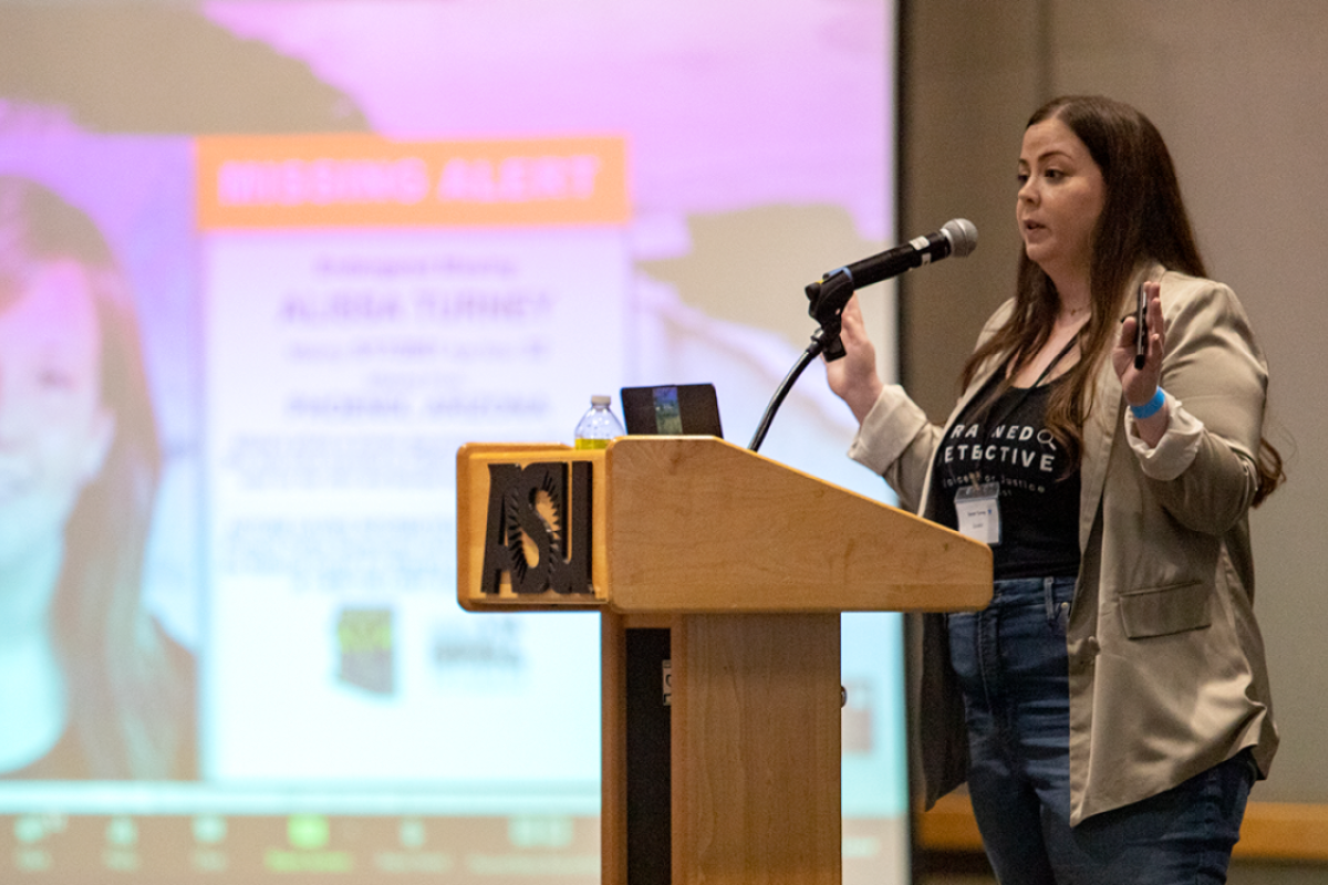 Woman standing behind a lectern speaking into a microphone.