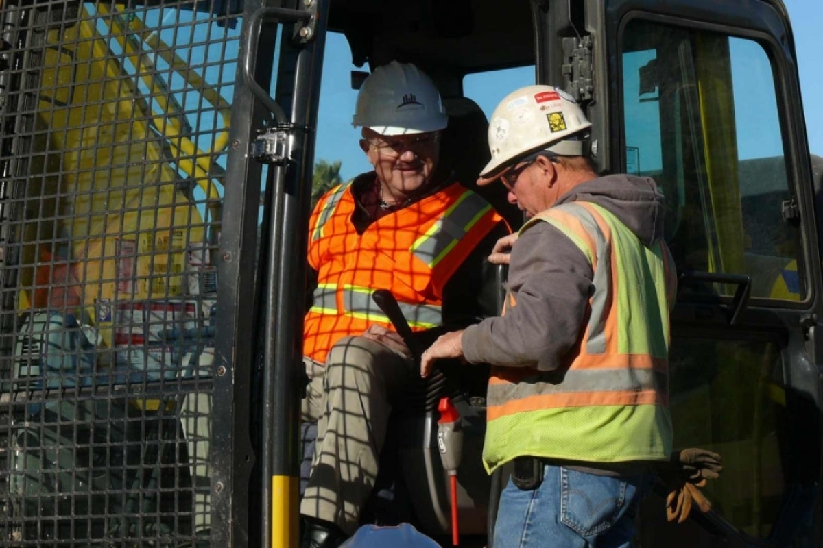 Edd Gibson sitting in a bobcat machine talking to an operator.