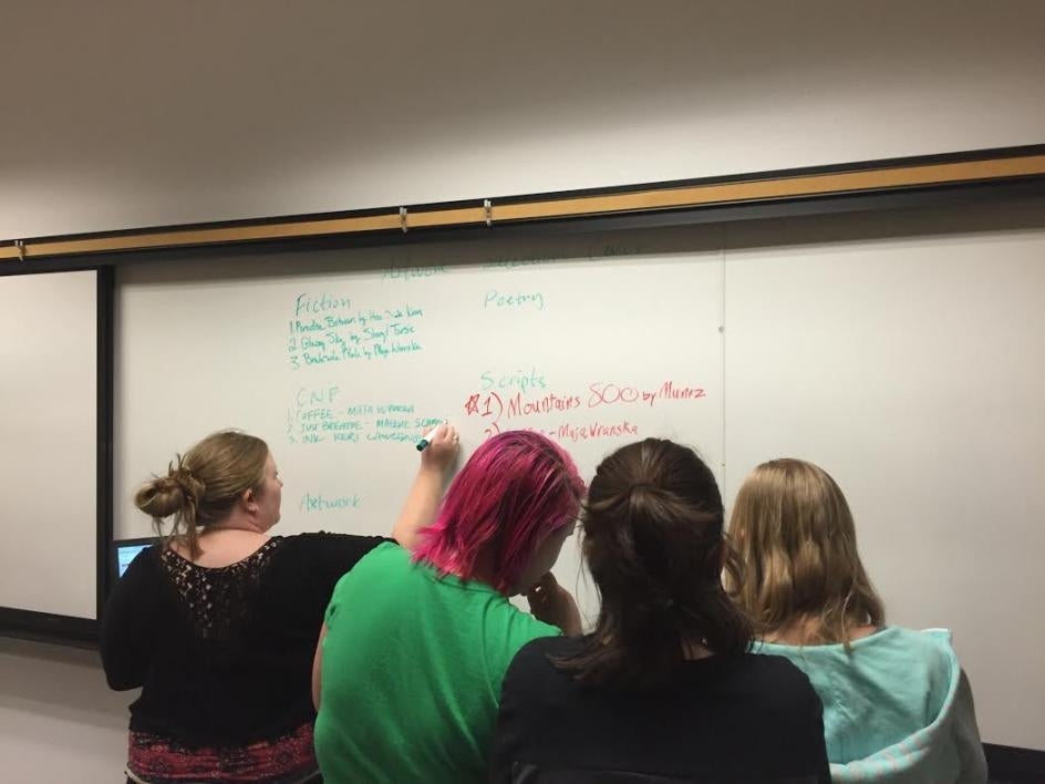 backs of heads of students grouped at whiteboard