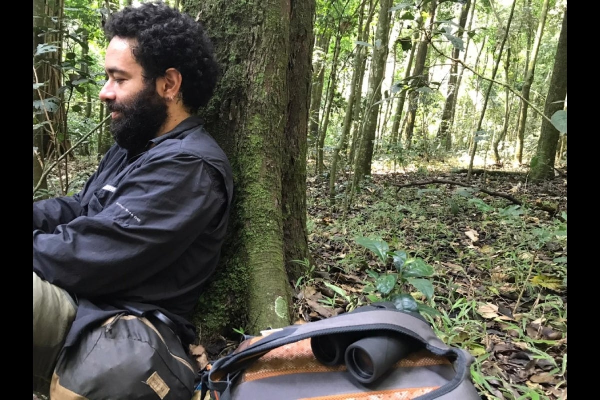 Man sitting against a tree trunk.