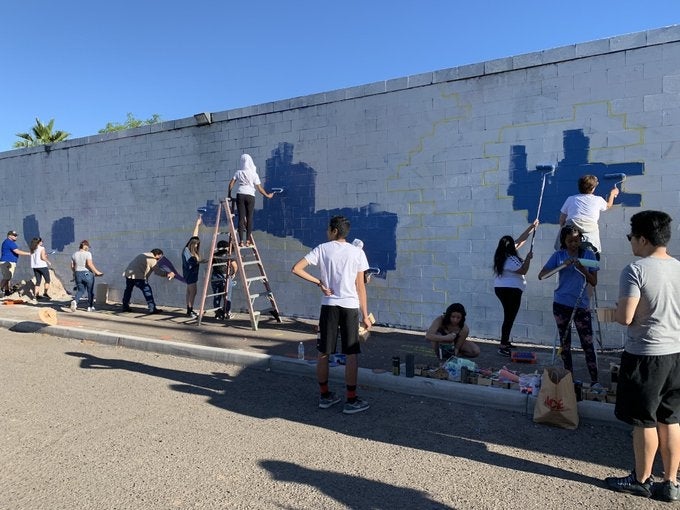 The class painting the mural with Hugo Medina