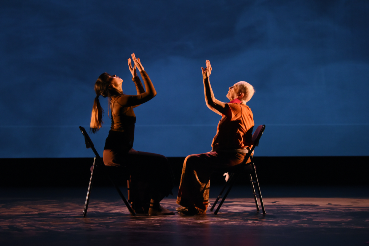 Mirabella resident and student during a performance sitting in chairs with arms raised.