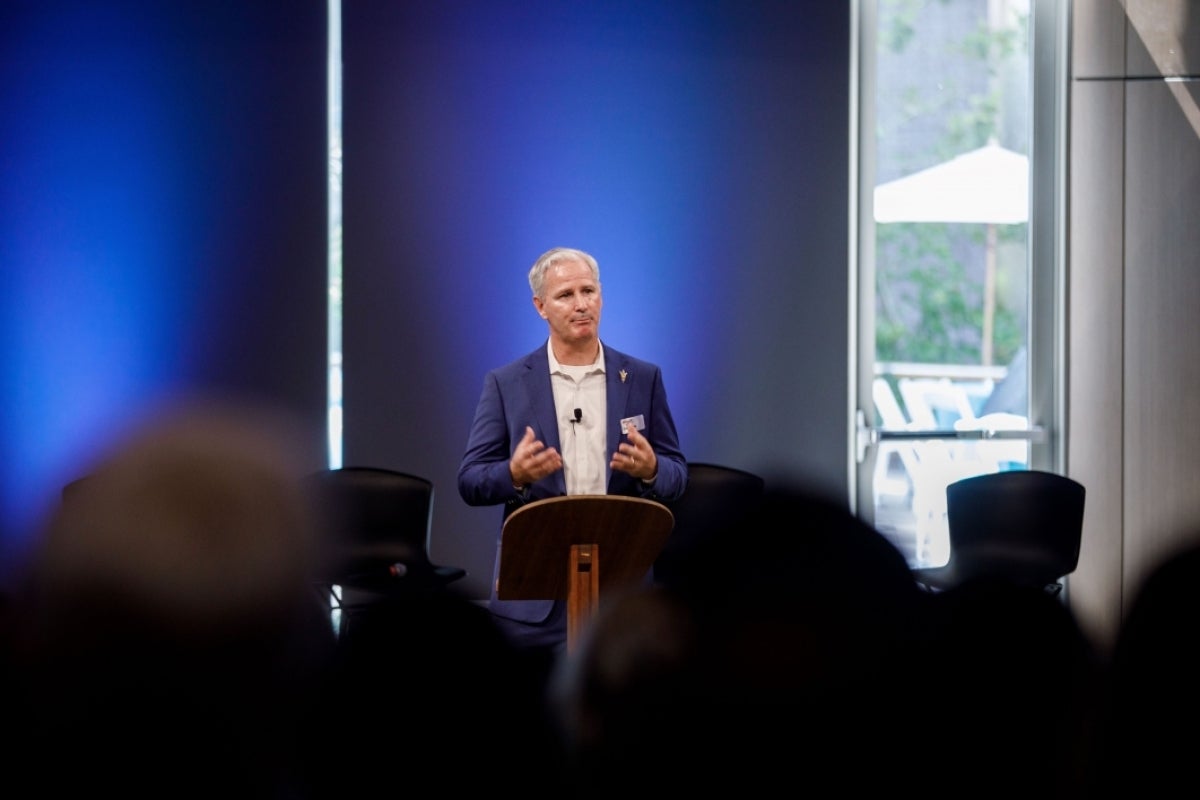 Dave White speaks at the kickoff event, standing at a podium in front of a crowd.