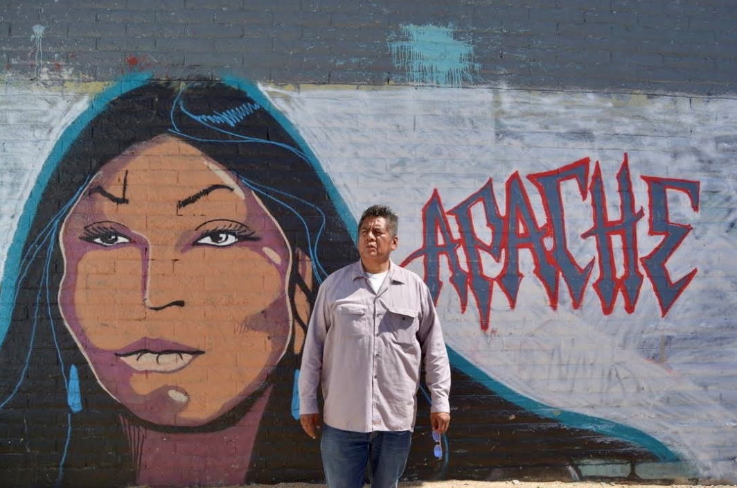 Douglas Miles standing in front of one of his murals