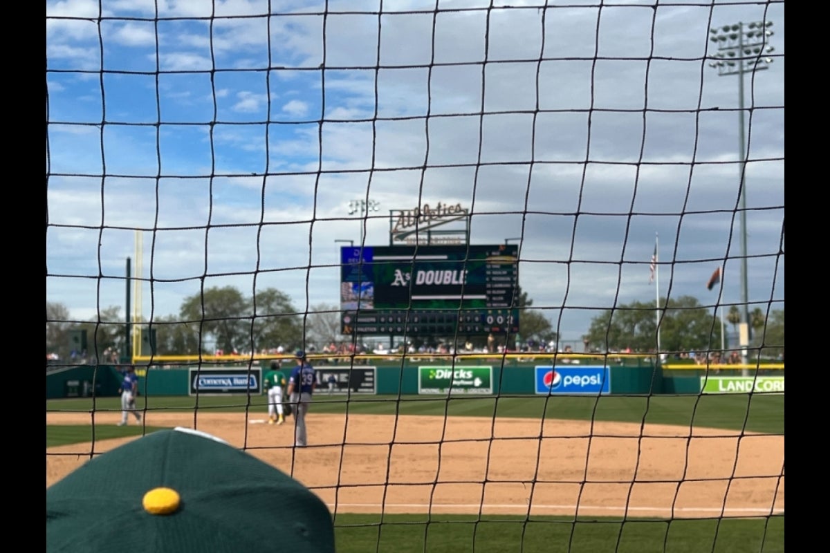 A scoreboard on a baseball field seen in the distance from the stands.