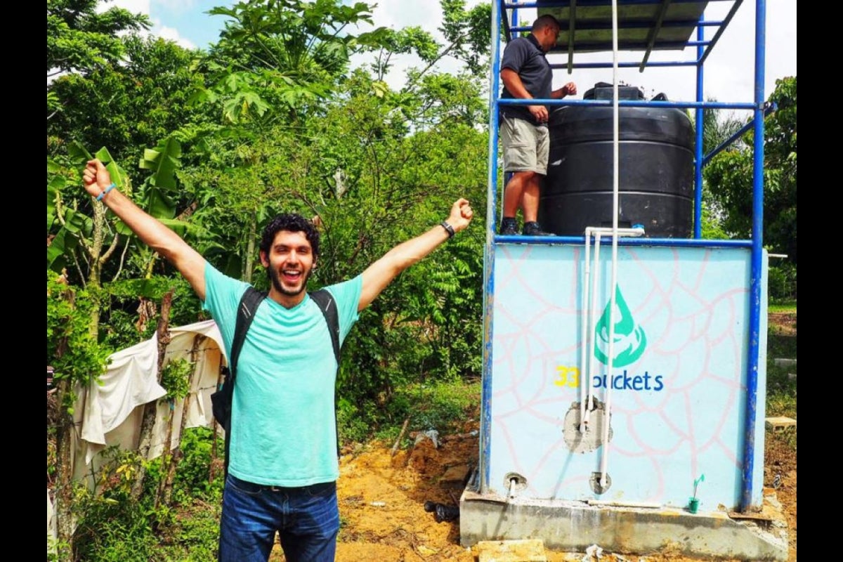 Mark Huerta celebrates in front of the finished water filtration system in the Dominican Republic.