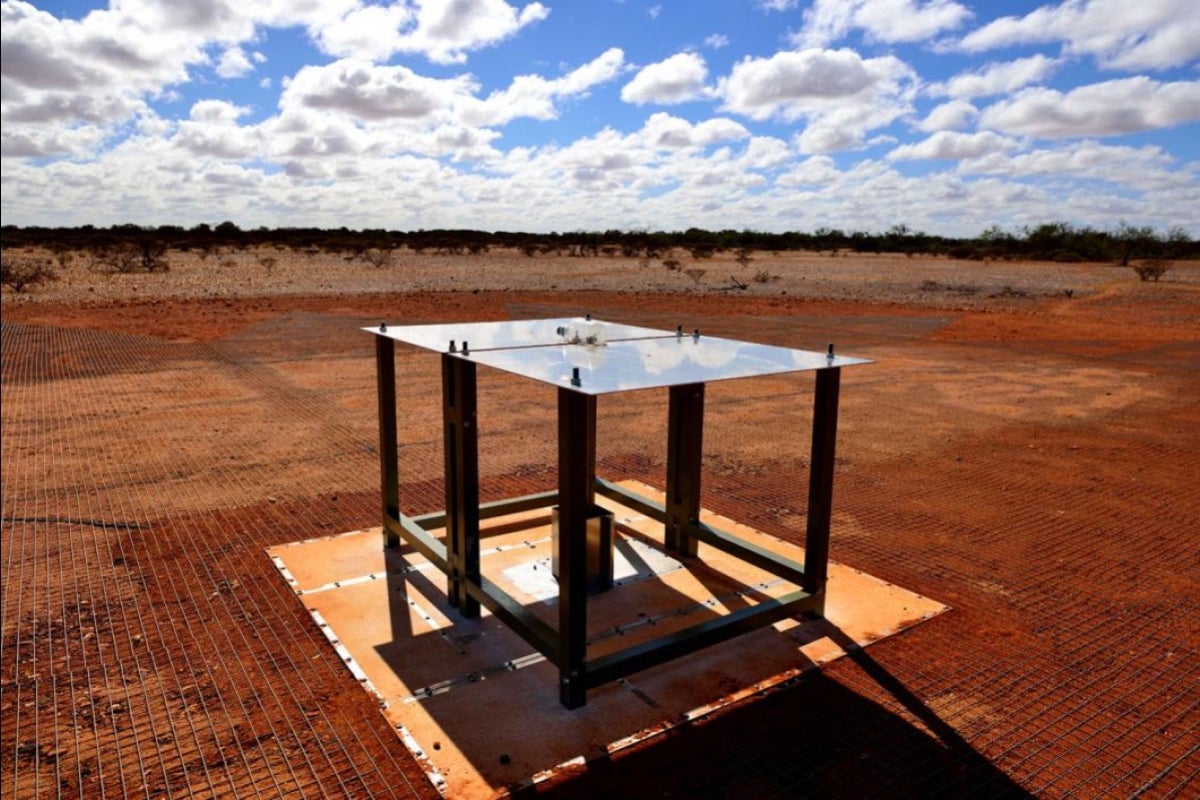 radio waves are collected by an antenna consisting of two rectangular metal panels mounted horizontally on fiberglass legs above a metal mesh